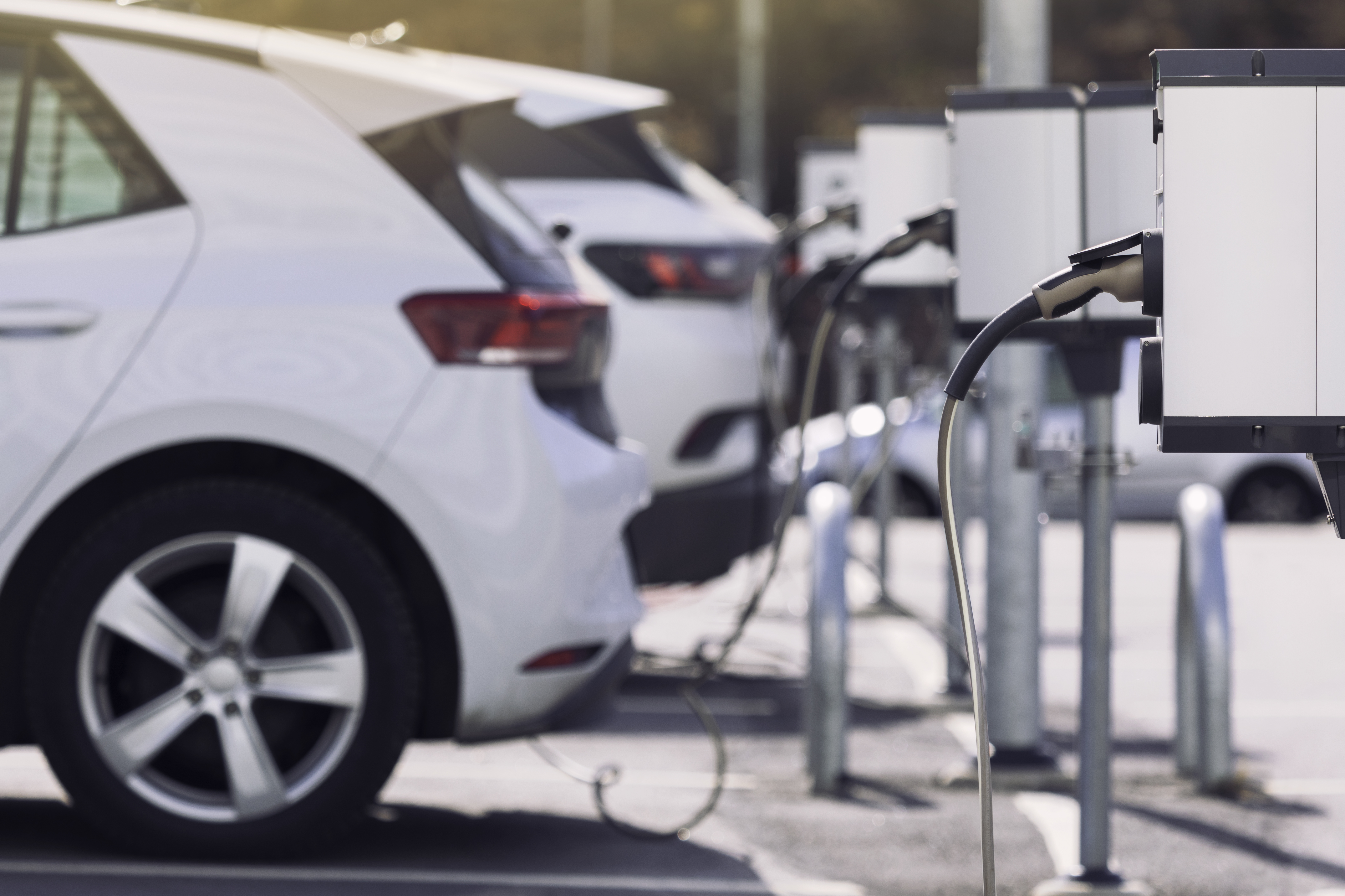 A row of white electric cars charging at an EV charging station.